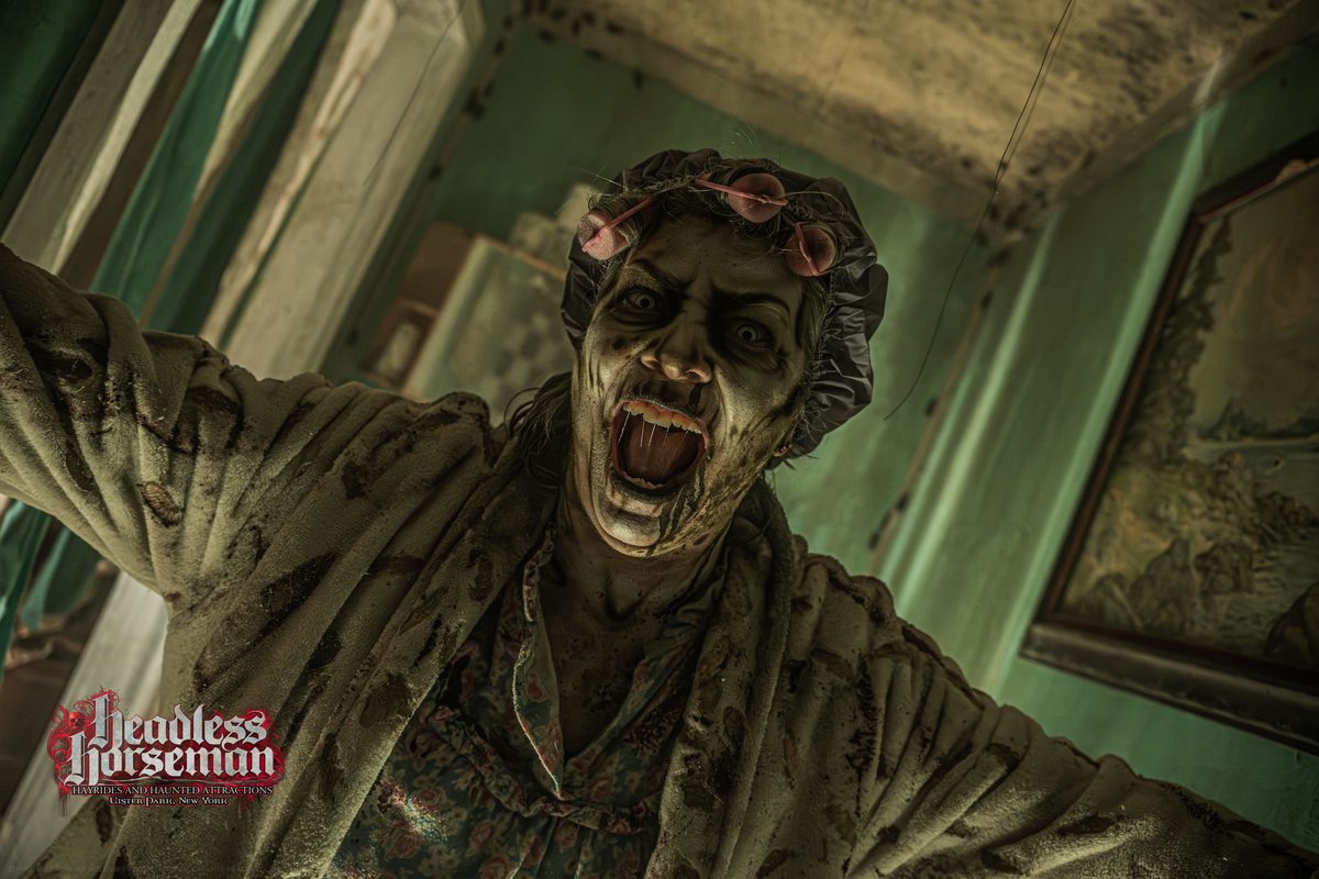 Costumed actor lunging toward guests in a haunted house room at Headless Horseman